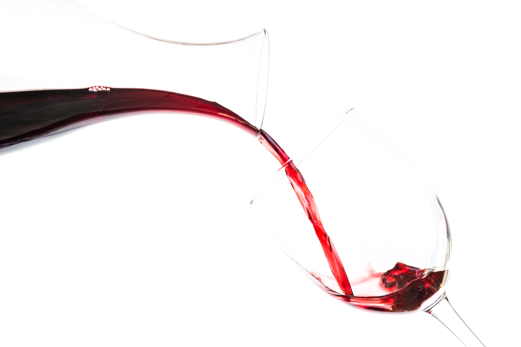 Red wine pouring into a glass against a white background
