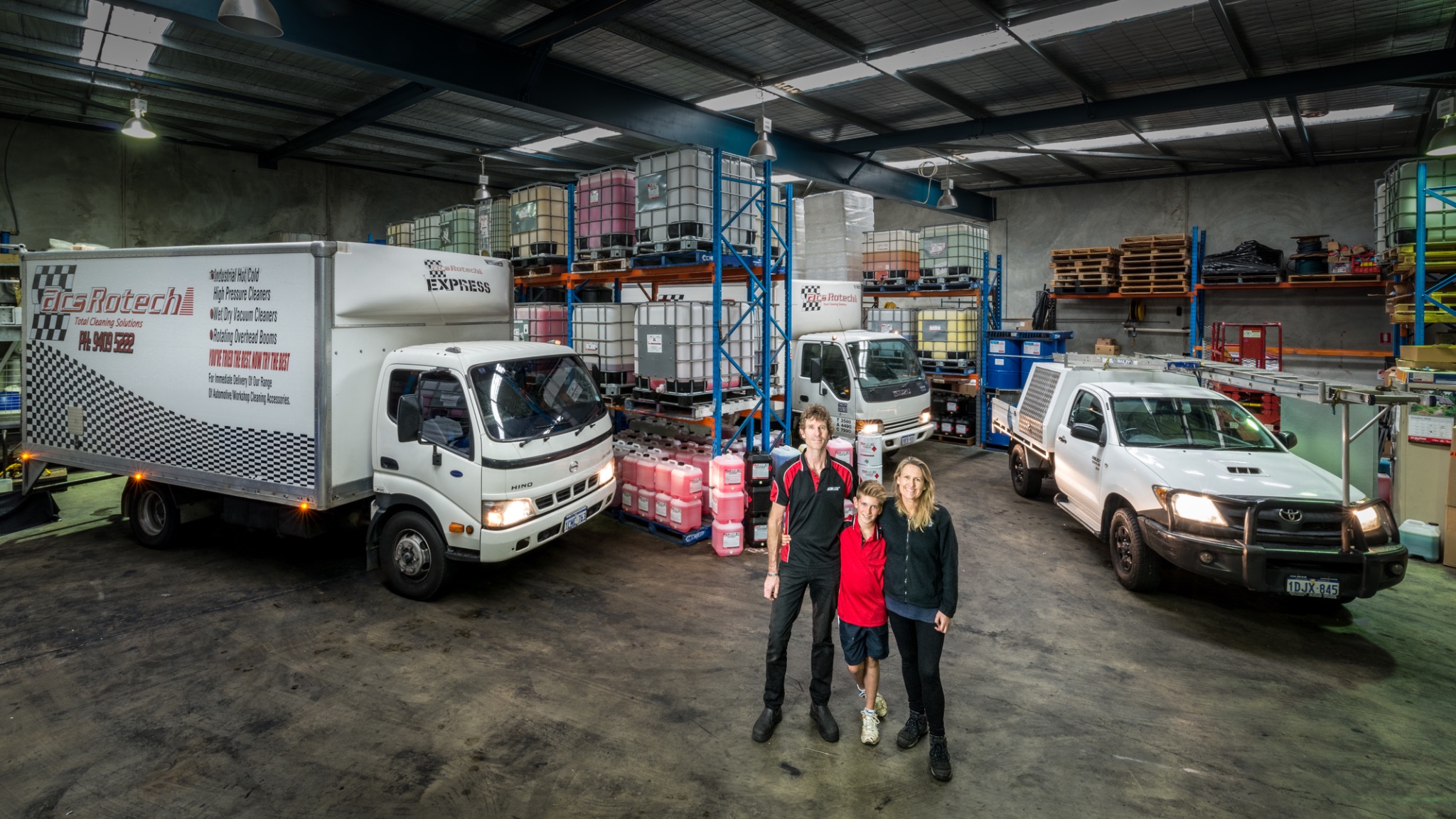 Team portrait with delivery vehicles inside a warehouse