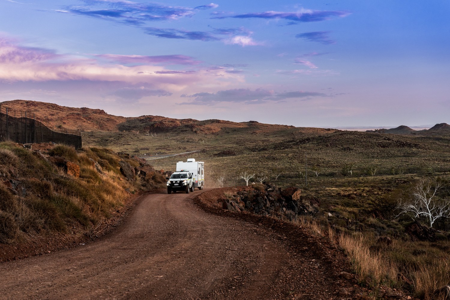 Truck on a winding earthworks road under a colourful sky