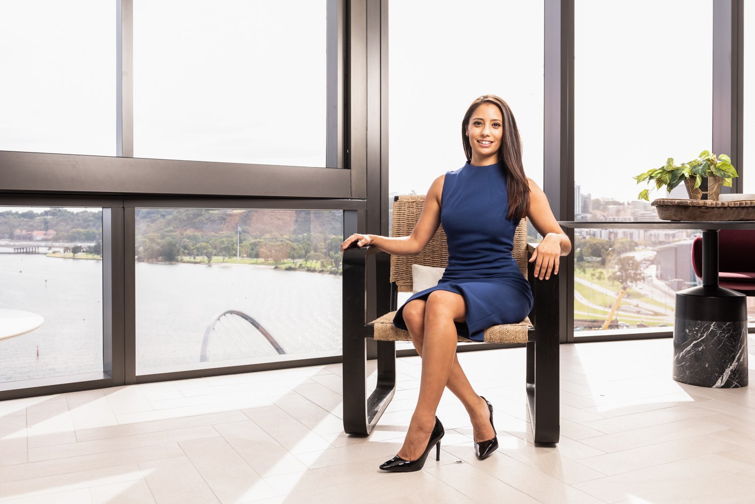 Seated business portrait beside tall windows overlooking the waterfront