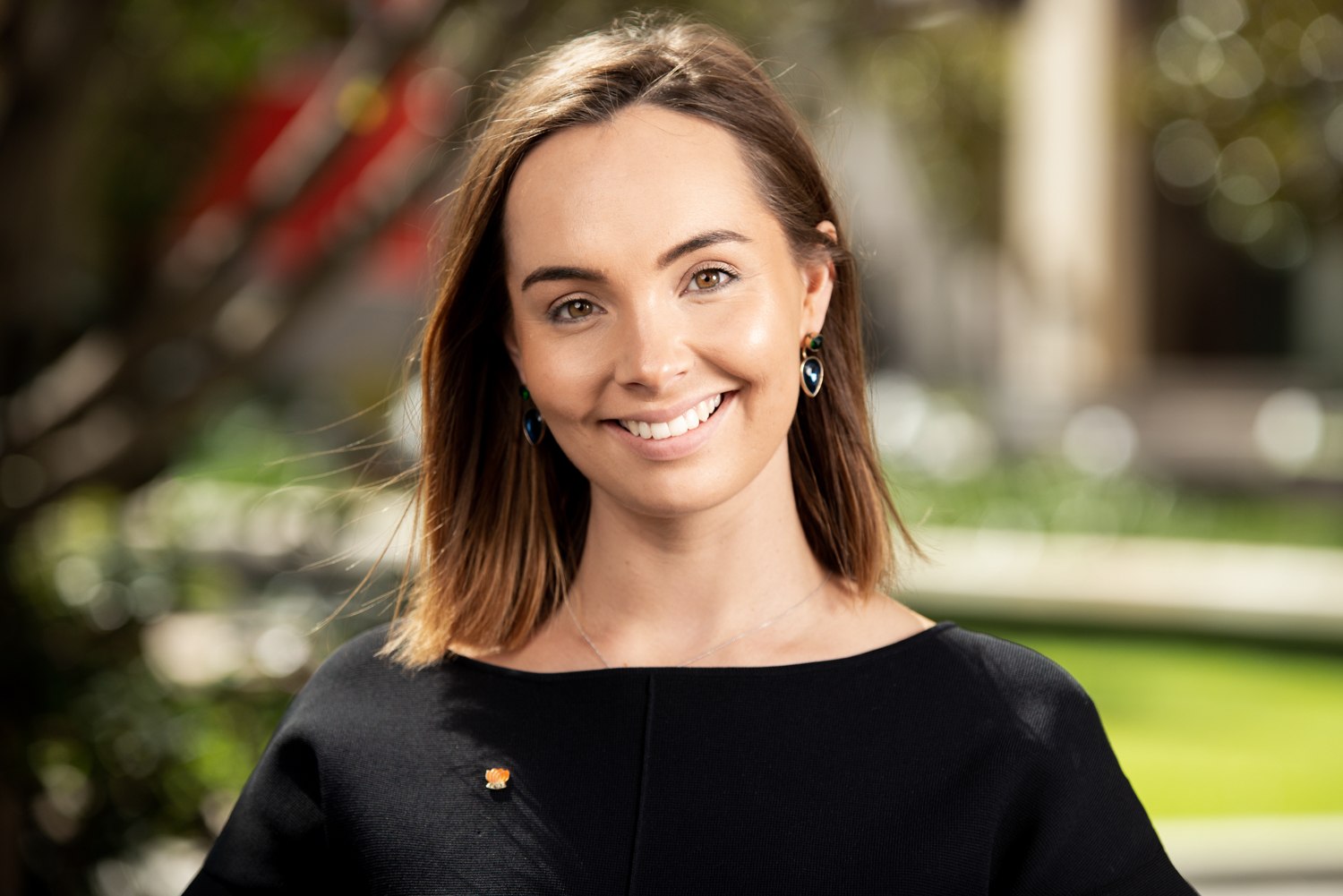 Professional headshot outdoors with a softly blurred background