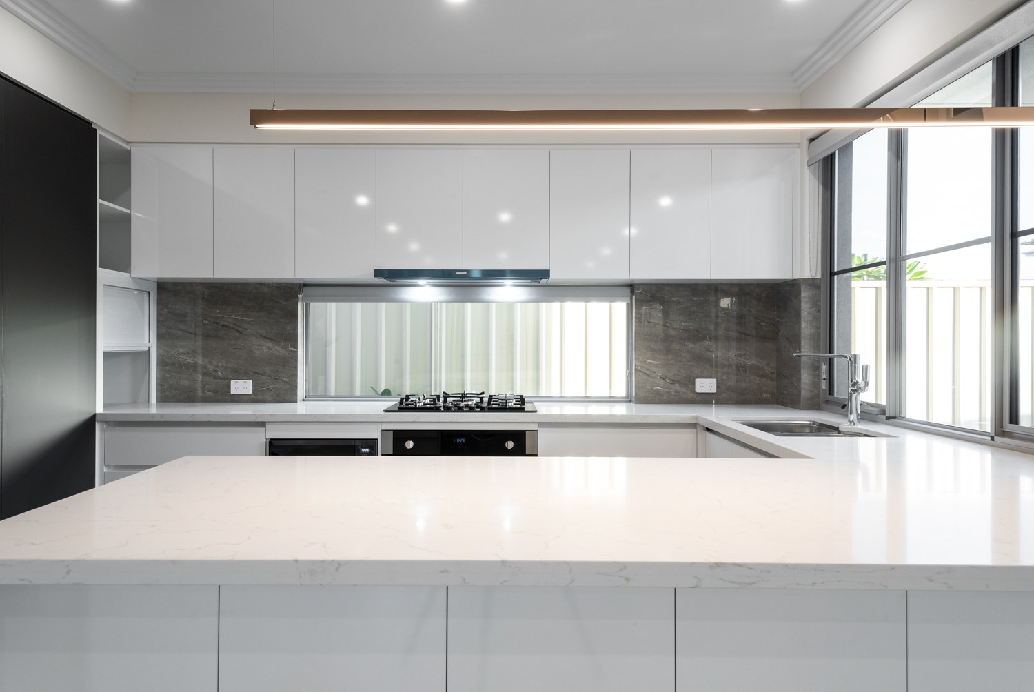 Modern white kitchen with reflective splashback in Yokine