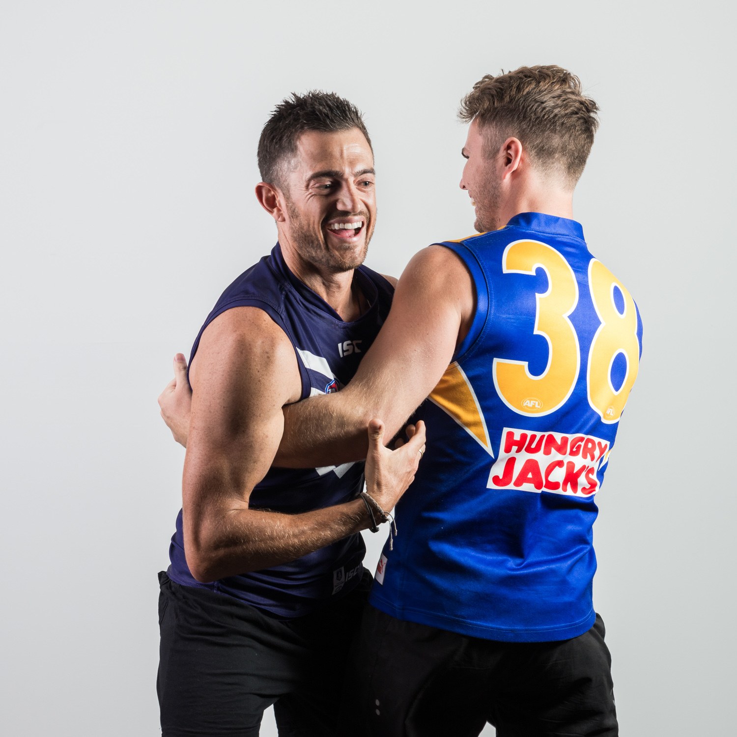 Two athletes in blue sports uniforms sharing a moment against a light background